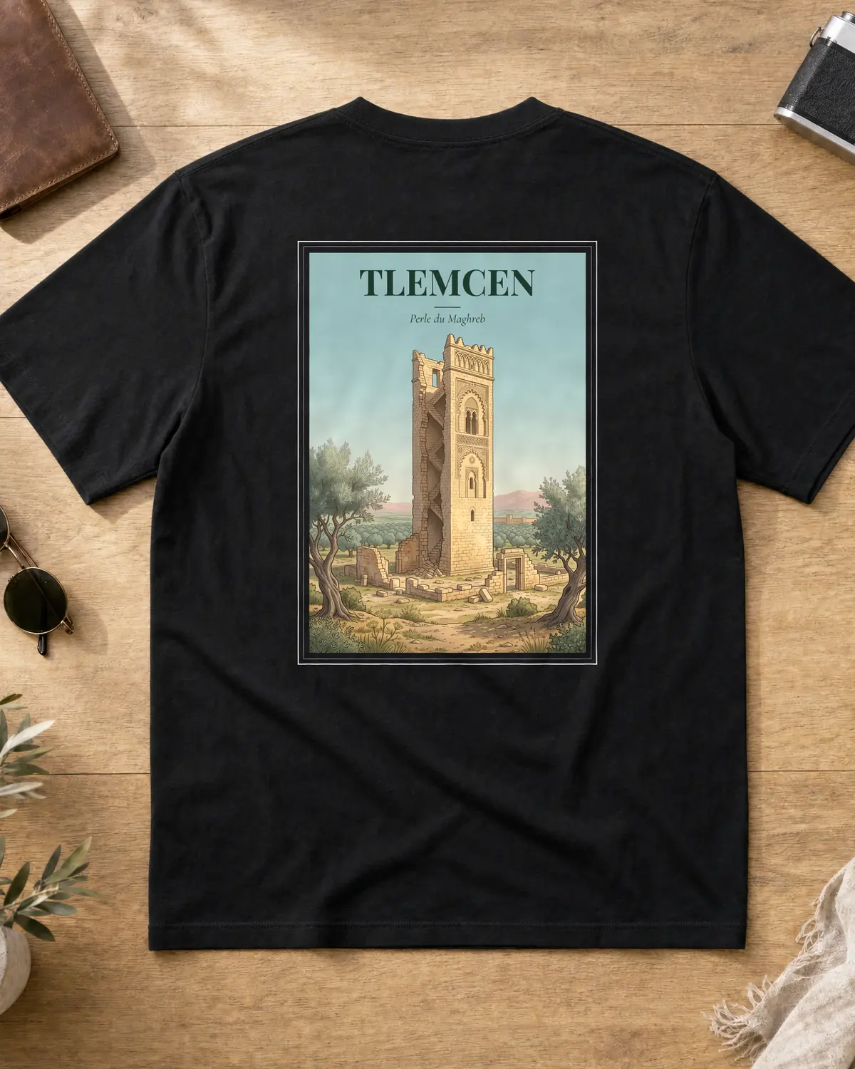 Black Tlemcen t-shirt back with a vintage poster of a tall stone minaret standing over ruins and olive trees, with the tagline Perle du Maghreb